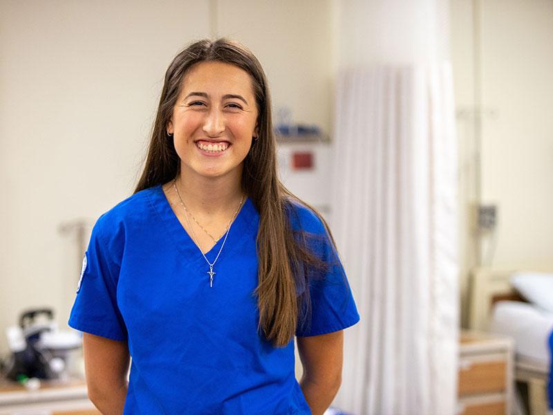 Woman in blue scrubs standing in nursing lab